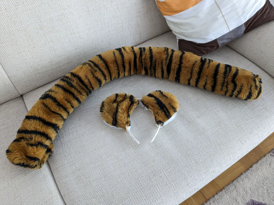 Photo of a hand-made tiger tail and ears lying on a white couch