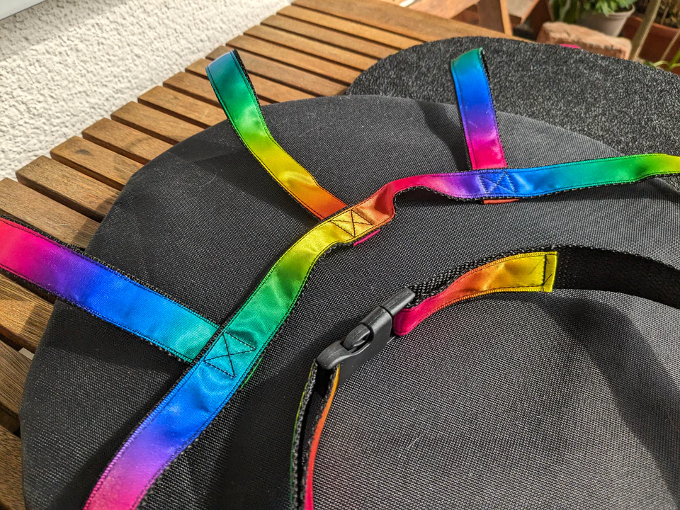 Close-up photo of two fursuit sandals on a wooden table. They have colorful rainbow straps and black rubber soles.
